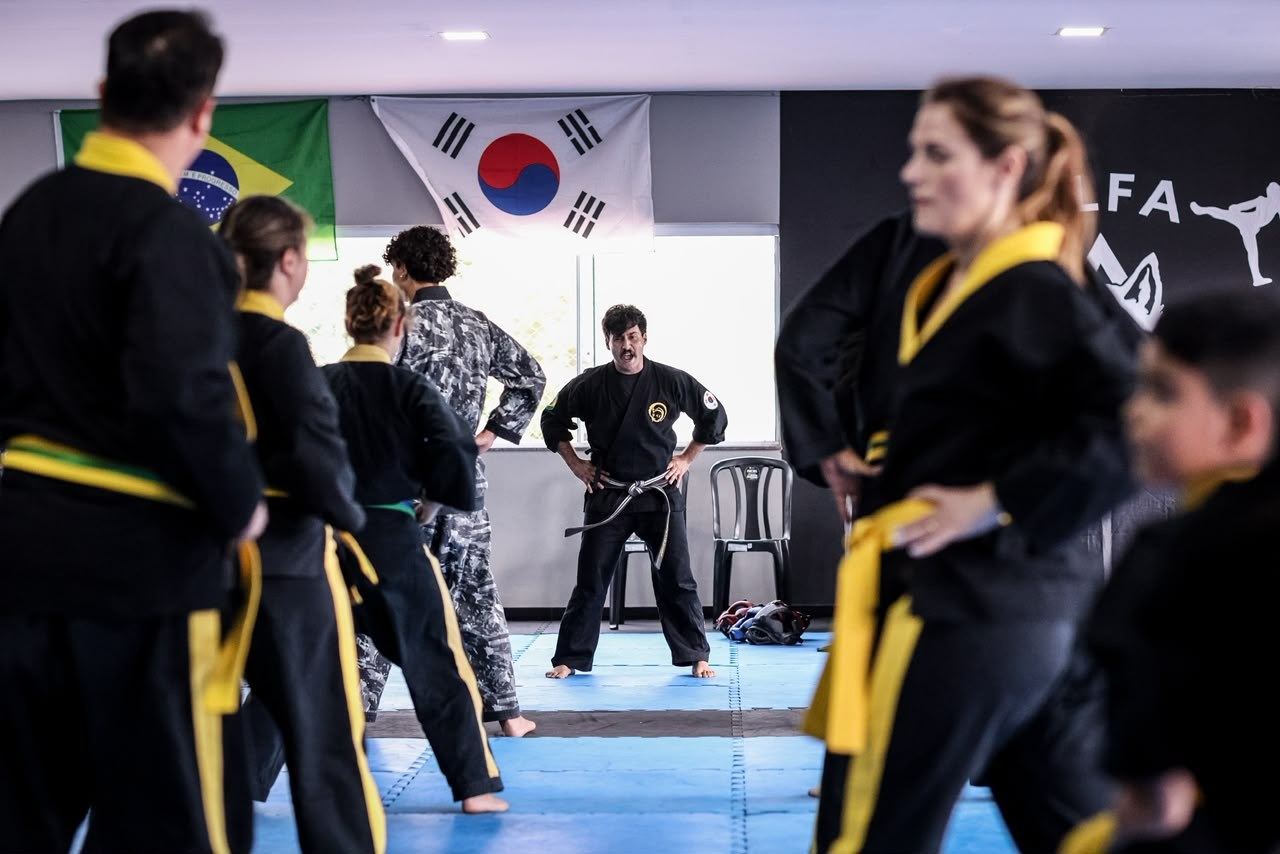 Aula em grupo numa escola filiada ao Instituto Brasileiro de Hapkido, sob as bandeiras do Brasil e da Coreia do Sul
