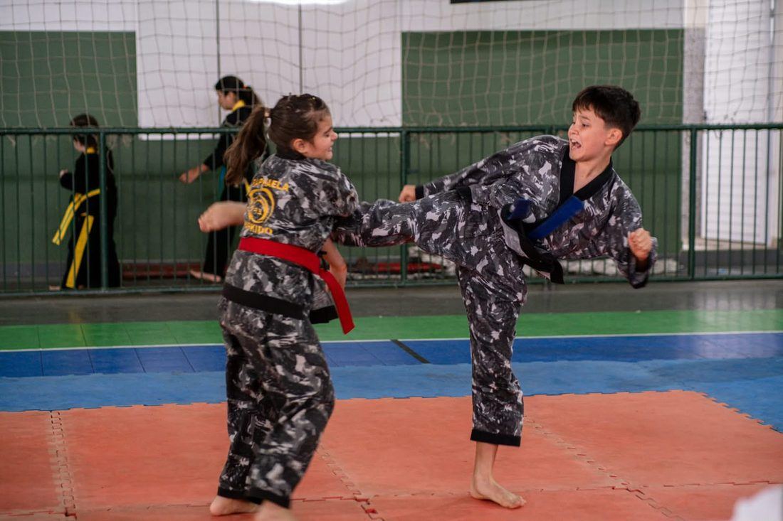 Alunos praticando técnica de chute em dupla no dojang