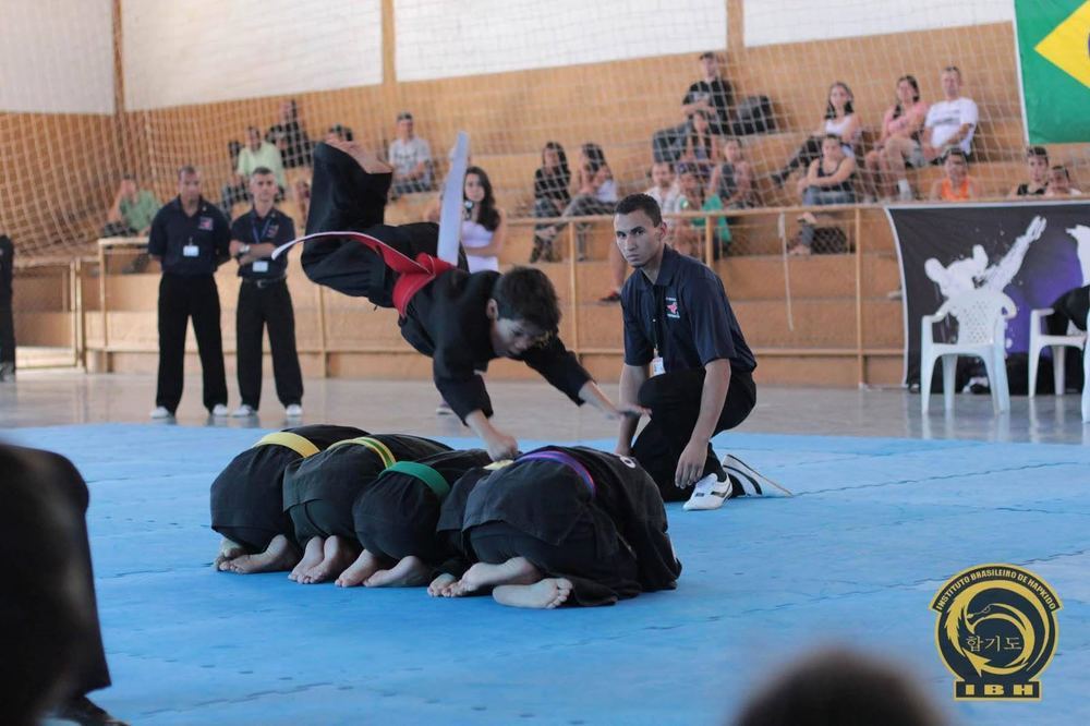 Criança em salto acrobático sobre colegas em apresentação