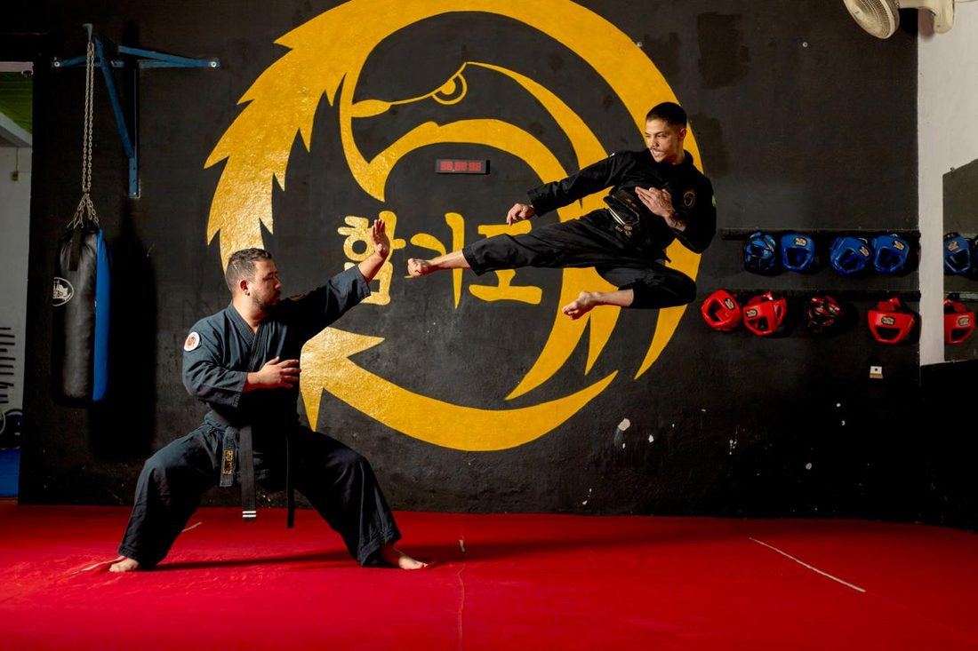 Instrutor aplicando chute voador com aluno, dojang do Instituto
